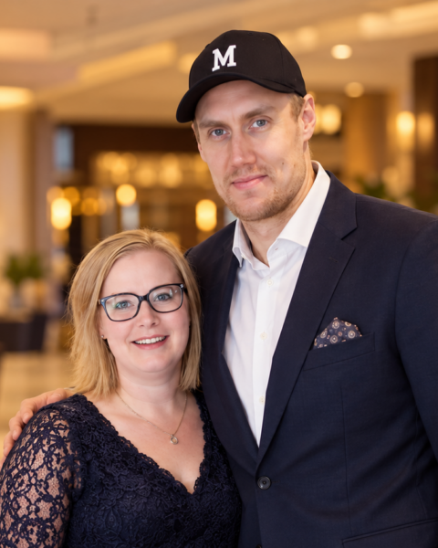 Marko Anttila ja hänen vaimonsa Heidi poseeraavat yhdessä lämpimästi valaistussa hotellin aulassa