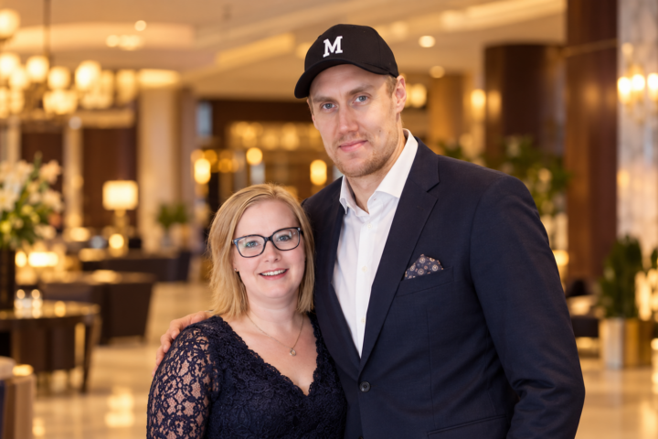 Marko Anttila ja hänen vaimonsa Heidi poseeraavat yhdessä lämpimästi valaistussa hotellin aulassa