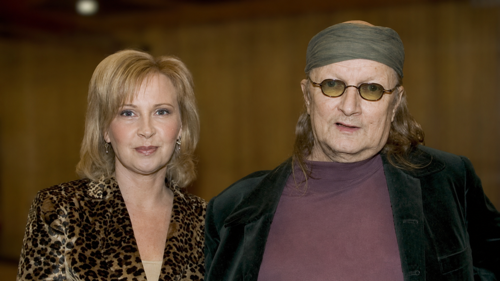 Sari Leskinen ja Juice Leskinen seisovat vierekkäin sisätiloissa sumeutettua puista taustaa vasten.