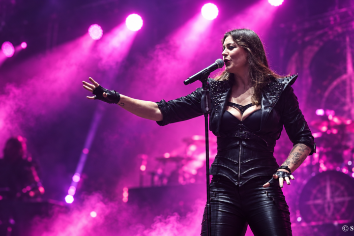 Nightwish-yhtyeen laulaja Floor Jansen esiintyy lavalla mustassa asussa kirkkaiden violettien ja pinkkien konserttivalojen loisteessa.