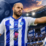Teemu Pukki HJK:n sinivalkoisessa pelipaidassa osoittaa kentällä joukkuetovereilleen suuntaa. Taustalla näkyvät jalkapallostadion, kannattajat ja Suomen liput.