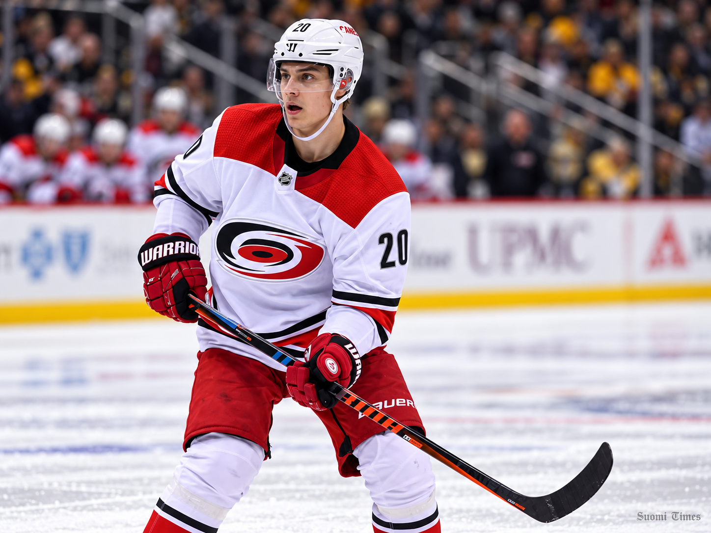 Carolina Hurricanesin peliasua käyttävä jääkiekkoilija Sebastian Aho luistelee kiekon kanssa NHL-ottelun aikana.